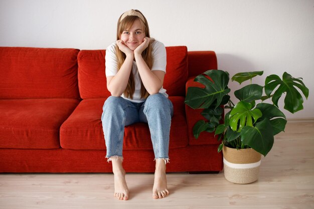 Em uma sala de estar aconchegante uma mulher feliz sentada apoiada em um sofá