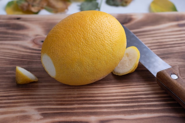 Em uma tábua, um limão amarelo cortado e uma faca
