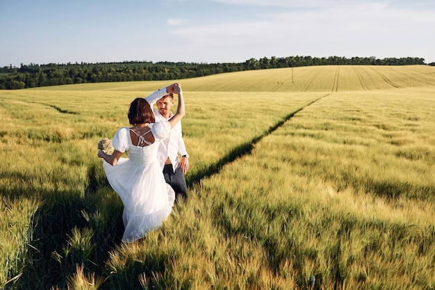 Em vestido e roupas formais Casal recém-casado Juntos no majestoso campo agrícola em dia ensolarado