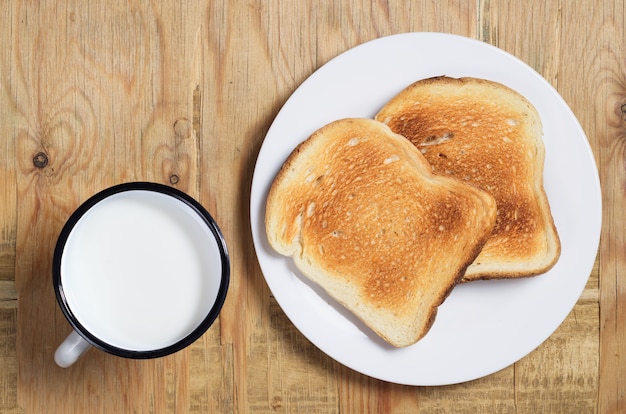 Emaillierte Tasse Milch und geröstetes Brot