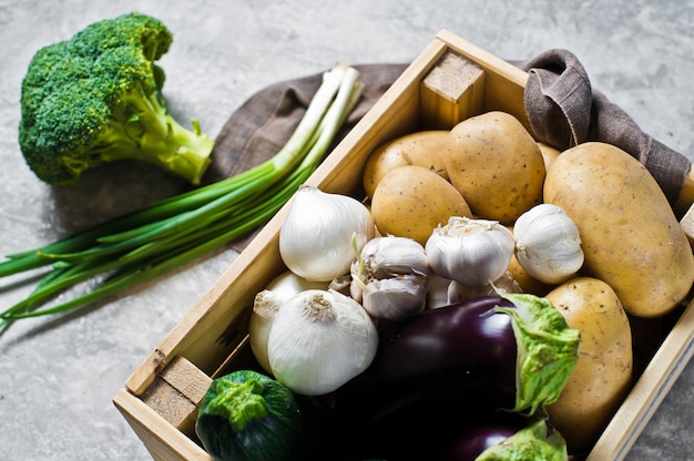 Embalagem de eco para legumes, livre de plástico. Caixa com legumes: batatas, cebolas, alho, berinjela, abobrinha, brócolis, cebolinha. Fazenda.