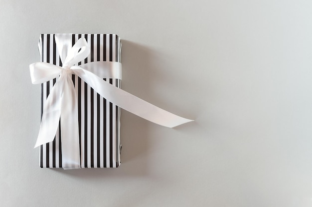 Embalaje de rayas blancas y negras de regalo. Vista superior de un estricto regalo monocromático con una cinta blanca.