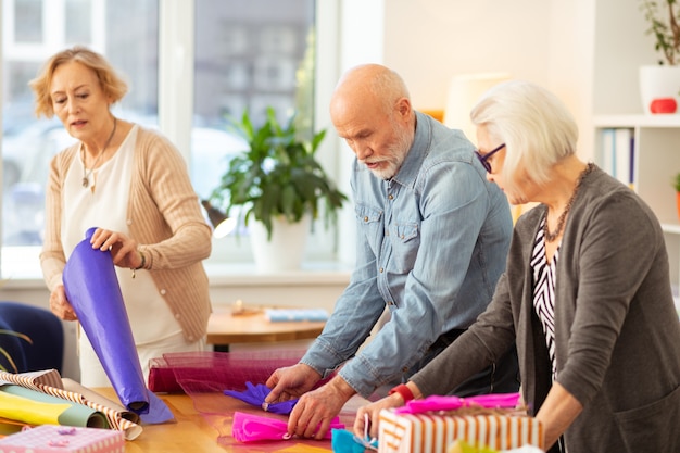 Embalaje de regalo. Gente agradable y alegre que se divierte mientras disfruta de su actividad creativa.