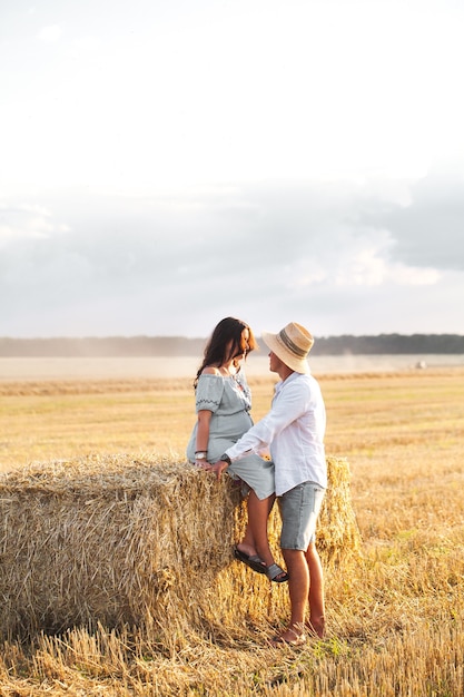 Embarazada de su marido en el pesebre. Hermosa pareja con girasoles