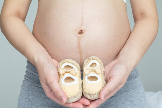 Foto embarazo concepto amoroso joven embarazada y sus zapatos de bebé