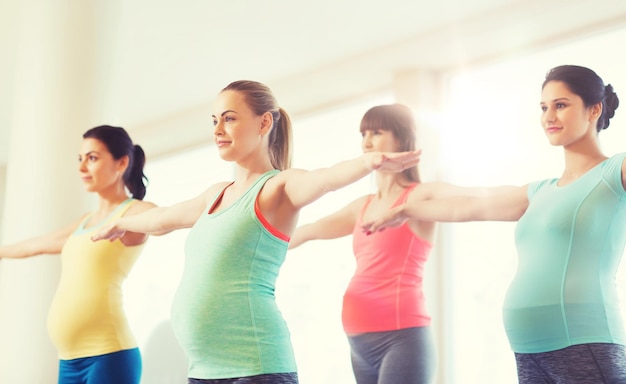 embarazo, deporte, fitness, personas y concepto de estilo de vida saludable - grupo de mujeres embarazadas felices haciendo ejercicio en el gimnasio