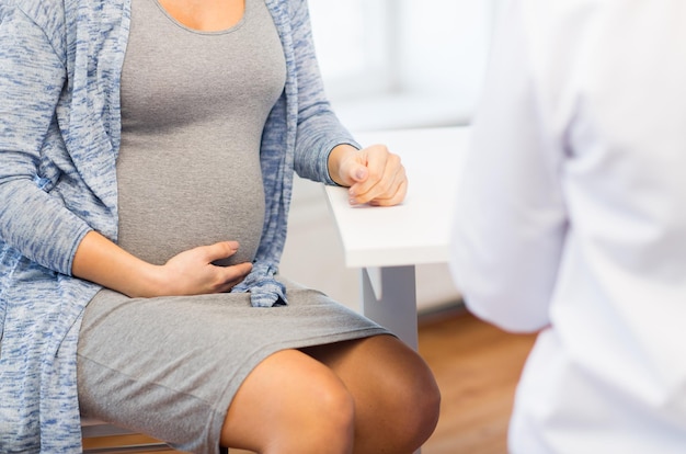 Embarazo, ginecología, medicina, atención de la salud y concepto de personas: cierre de una mujer embarazada y un médico ginecólogo reunidos en el hospital