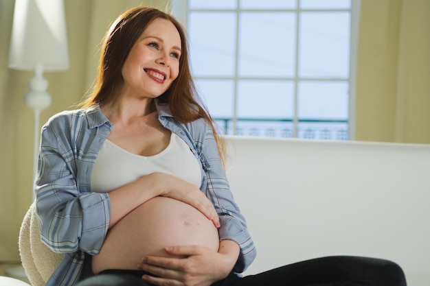 Embarazo maternidad gente expectativa futuro mujer embarazada tocando gran panza sentada en el sofá en