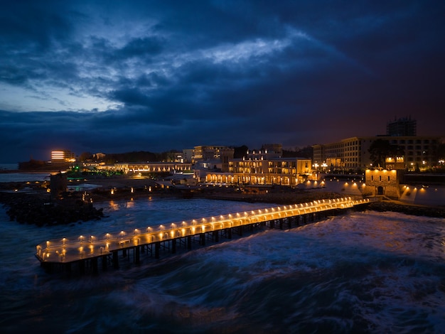 Embarcadero iluminado con un cielo espectacular sobre el tormentoso mar oscuro al atardecer Varna Bulgaria