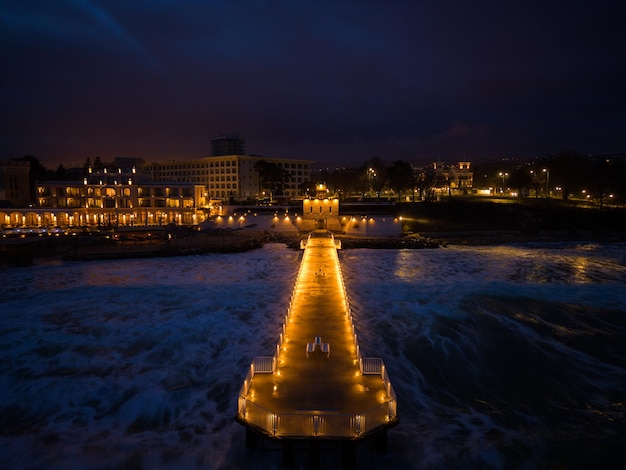 Embarcadero iluminado con un cielo espectacular sobre el tormentoso mar oscuro al atardecer Varna Bulgaria