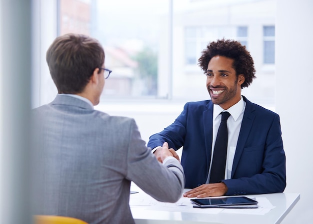 Embarcando em uma parceria comercial positiva Foto de um empresário sorridente apertando as mãos de um colega em seu escritório