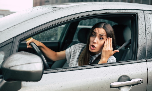 Embarque de trânsito motorista agressivo acidente de carro retrato em close-up descontente mulher zangada dirigindo carro e gritando com alguém com a mão punho no ar expressão humana negativa