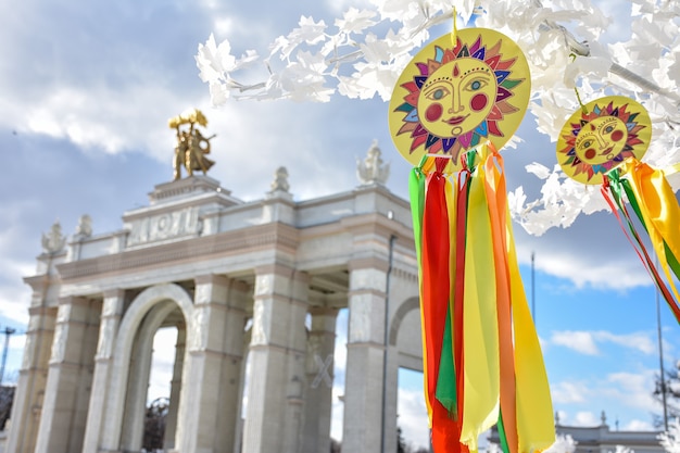 emblema del sol con cintas de colores en las ramas del árbol blanco cintas multicolores contra la piedra