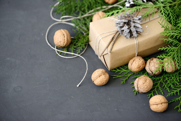 Embrulhando pacotes de Natal rústica eco com papel marrom, string e ramos de abeto natural em fundo escuro