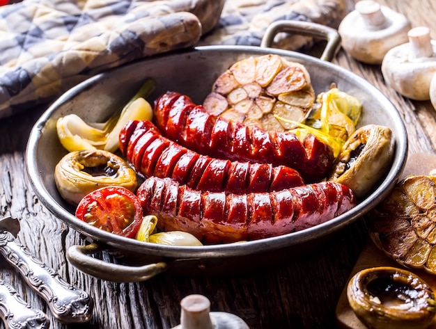 Embutidos Asa las salchichas. Chorizo a la plancha con champiñones al ajillo, tomates y cebollas.