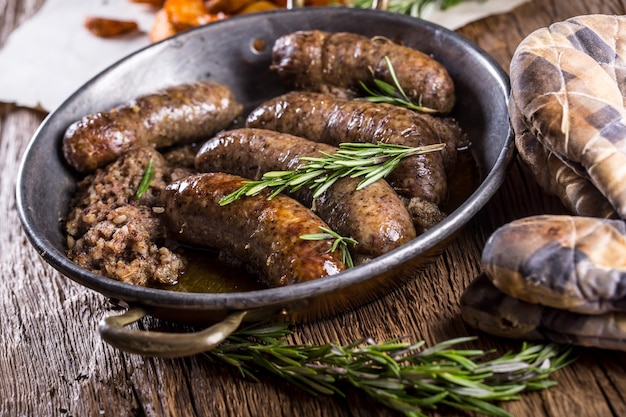 Embutidos. Chorizo de cerdo asado en una sartén con patatas y romero.