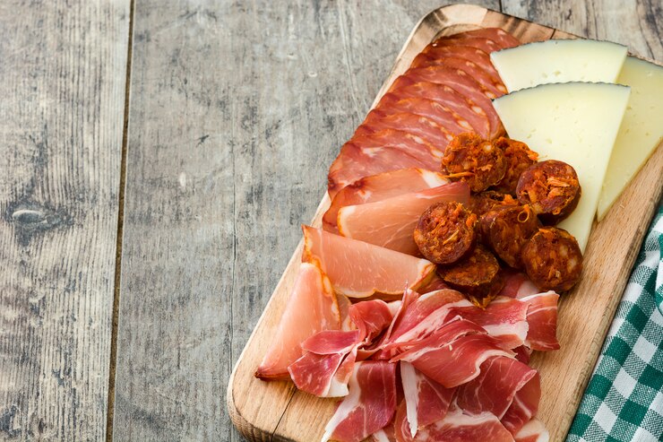 Foto embutidos españoles embutidos queso, chorizo y jamón sobre mesa de madera