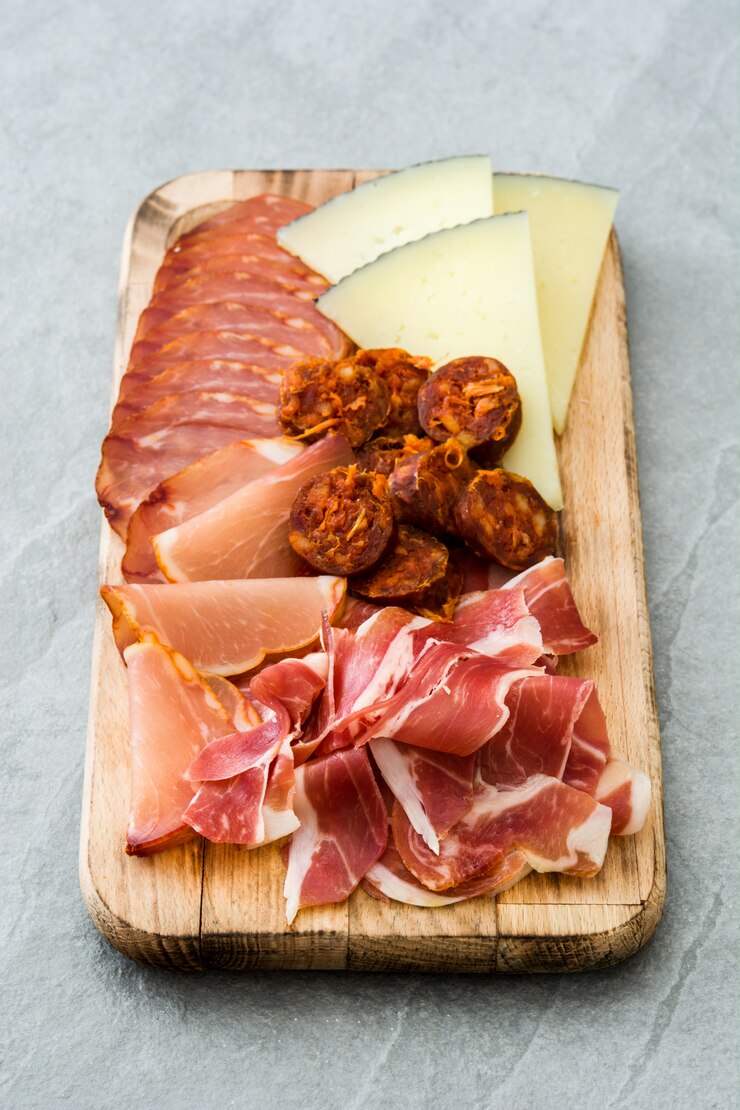 Foto embutidos españoles de embutidos queso, chorizo y jamón sobre piedra gris