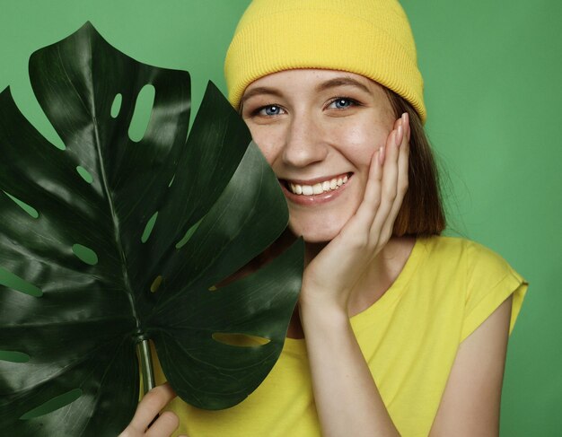 Emoção de estilo de vida e conceito de pessoas Mulher bonita sorridente atrás de folha grande