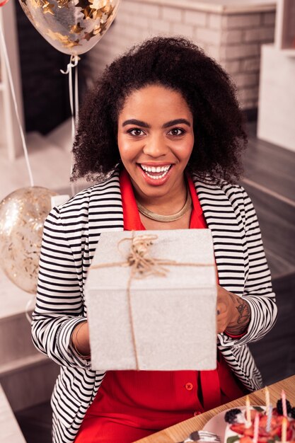 Emoción de felicidad. Alegre mujer feliz mirándote mientras recibe un regalo