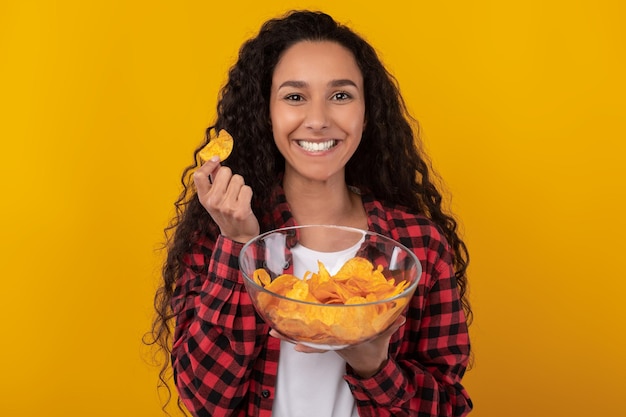 Emocionada dama latina comiendo deliciosas papas fritas