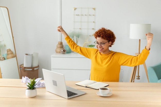 Emocionada feliz mujer afroamericana eufórica ganadora estudiante mirando la computadora portátil pasó el examen de lectura