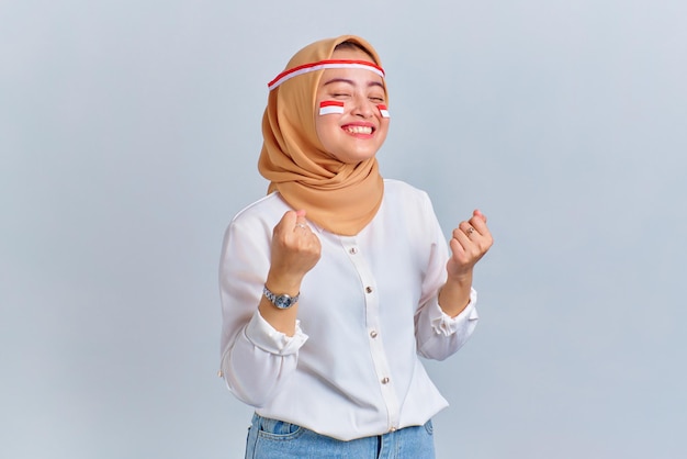 Emocionada joven asiática celebrando el día de la independencia de Indonesia aislada de fondo blanco