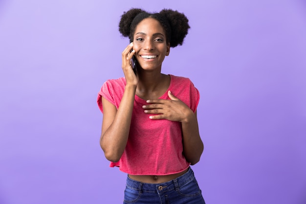 Emocionada mujer afroamericana sonriendo y hablando por teléfono móvil, aislado