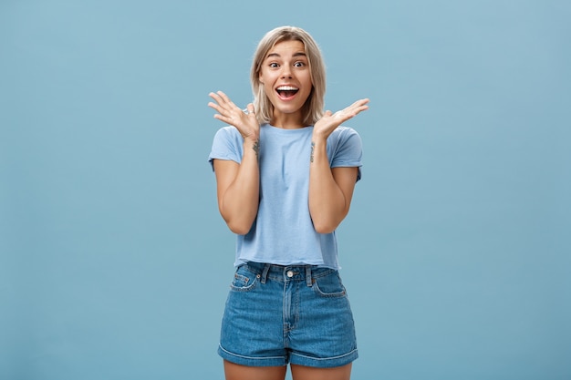 Emocionada mujer feliz entusiasta en camiseta de moda y pantalones cortos aplaudiendo de asombro sonriendo ampliamente, sorprendido y alegre