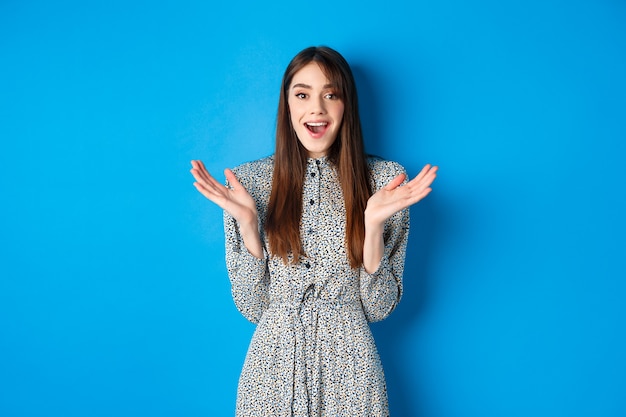 Emocionada mujer hermosa aplaude y felicita, alabando el buen trabajo, aplaudiendo a la cámara y sonriendo, de pie en azul.