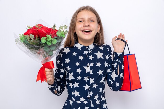 Emocionada niña hermosa en feliz día de San Valentín con ramo de flores con bolsa de regalo