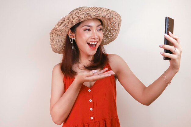 Emocionada y sonriente joven asiática señalando con el dedo el smartphone en la mano