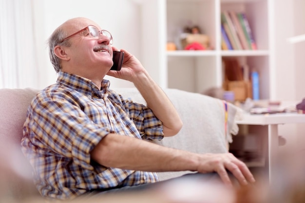 Emocionado anciano padre o abuelo hablando por teléfono