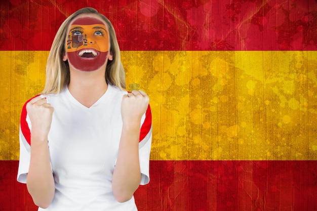 Foto emocionado fan de españa con pintura facial animando contra la bandera de españa en efecto grunge