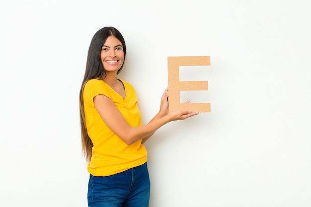 emocionado, feliz, alegre, sosteniendo la letra E del alfabeto para formar una palabra o una oración.