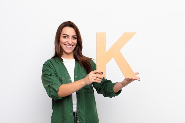 emocionado, feliz, alegre, sosteniendo la letra K del alfabeto para formar una palabra o una oración.