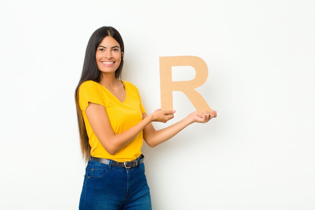 emocionado, feliz, alegre, sosteniendo la letra R del alfabeto para formar una palabra o una oración.