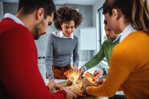 Emocionado grupo de empresarios almorzando pizza