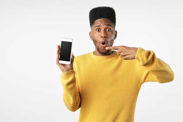 Emocionado joven afroamericano en pose casual aislado sobre fondo de pared blanca