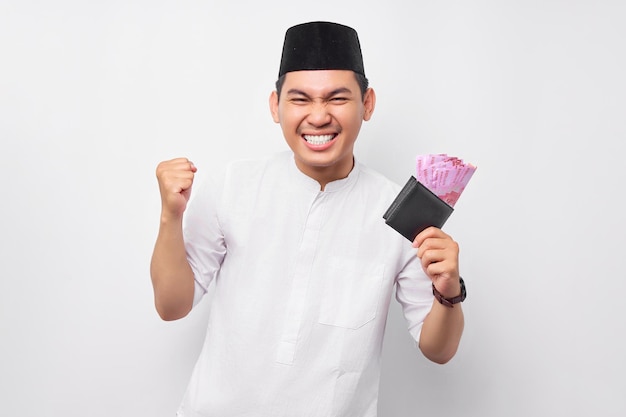 Emocionado joven asiático musulmán guapo sosteniendo billetera de dinero en efectivo completo aislado sobre fondo blanco Concepto de estilo de vida islámico religioso de la gente