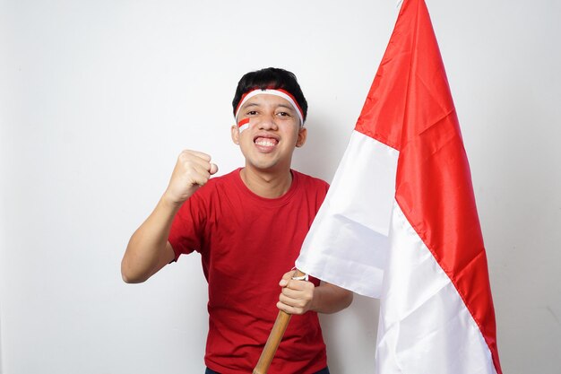 Foto emocionado joven asiático sosteniendo la bandera de indonesia mientras celebra el día de la independencia de indonesia