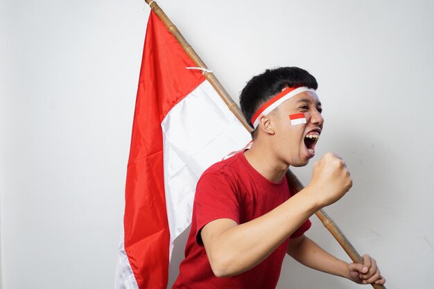 Emocionado joven asiático sosteniendo la bandera de Indonesia mientras celebra el Día de la Independencia de Indonesia