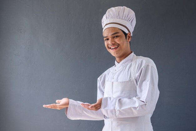 Emocionado joven chef masculino presentando algo al lado mostrando un producto