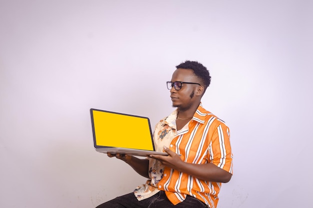 Emocionado joven negro sosteniendo portátil mirando a la computadora portátil