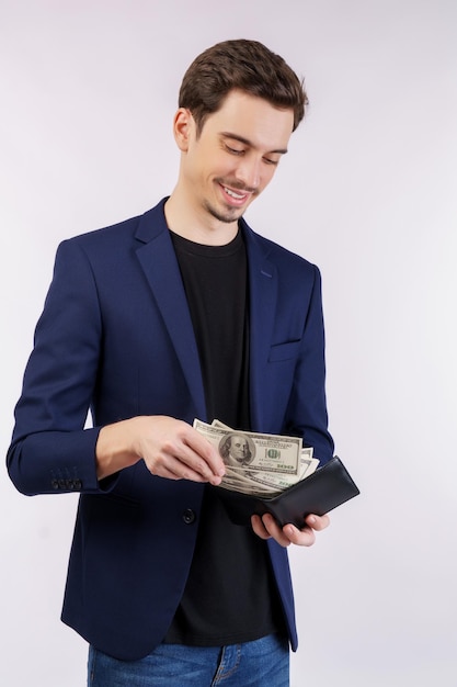 Emocionado joven poniendo billetes en billetera aislado fondo blanco studio