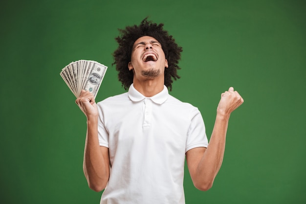 Emocionado joven rizado africano emocional mostrando dinero.