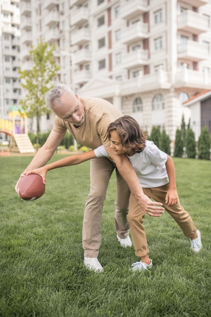 Emocionado. Niño de pelo oscuro y su padre mirando emocionados mientras juega a la pelota