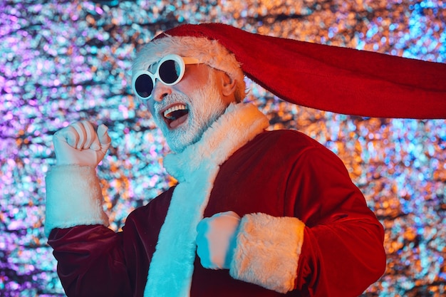 Emocionado Santa Claus en gafas de sol divirtiéndose durante la fiesta