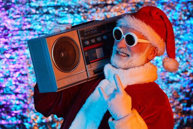 Emocionado Santa Claus en gafas de sol escuchando música en estéreo y bailando