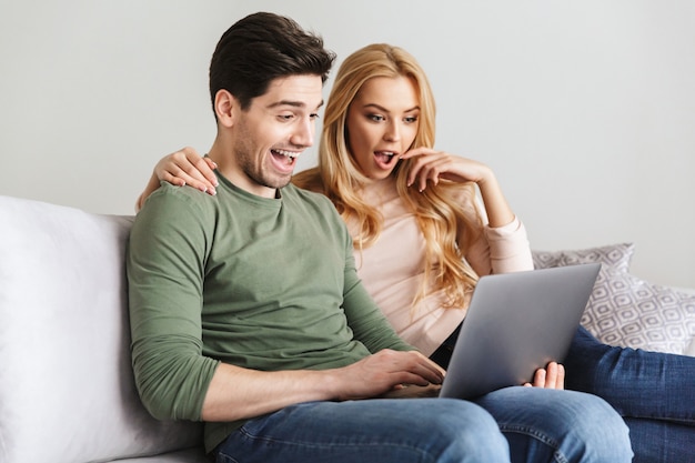 Emocionado sorprendido joven pareja amorosa con ordenador portátil.